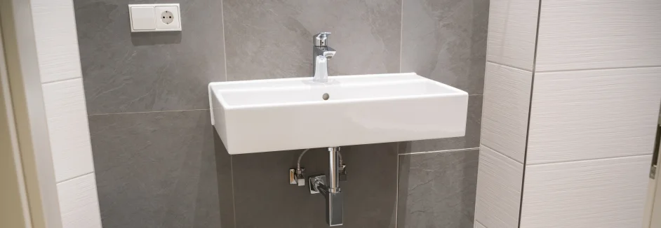 Weißes Waschbecken an grauer Wand